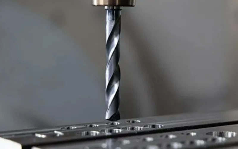 Drill bit cutting a hole into a metal workpiece