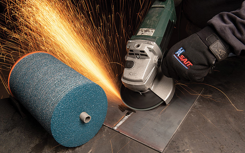 Worker grinding metal with an angle grinder fitted with a fiber disc
