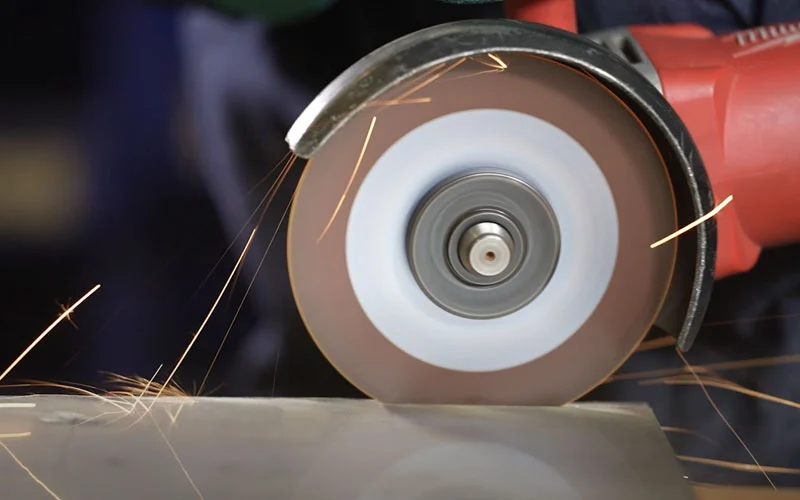 Worker grinding aluminum with an abrasive wheel