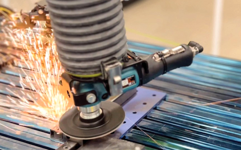 Autobrade surface finishing tool generating sparks while finishing a metal workpiece.